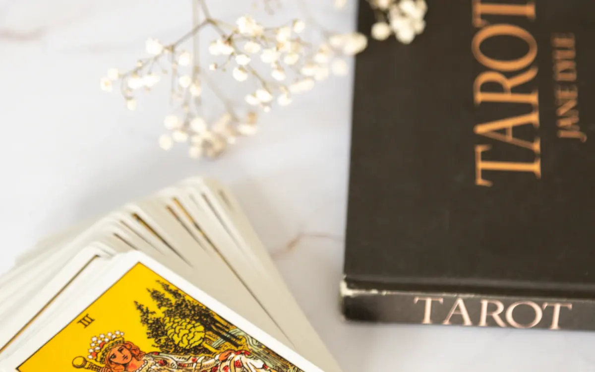 Tarot cards beside a book and candle